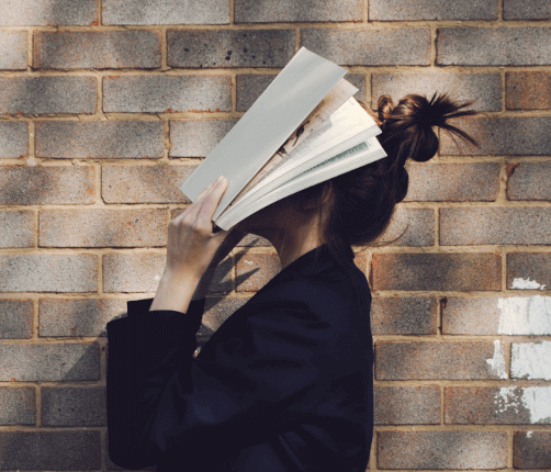 Woman holding book in front of face